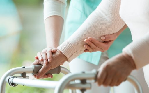 Close-up photo of patient's hands placed on metal walker
